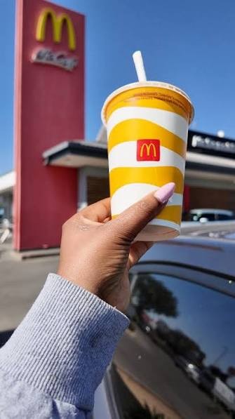 A McDonald's cup held up outside a restaurant
