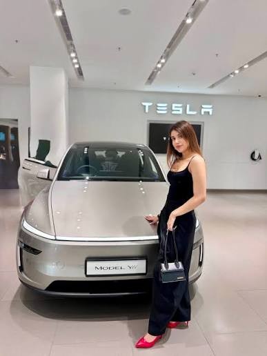 A woman standing beside a Tesla Model Y in a showroom